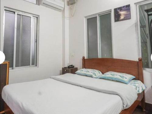1 Schlafzimmer mit 2 Betten und 2 Fenstern in der Unterkunft Hilltop Lodge in Guwahati