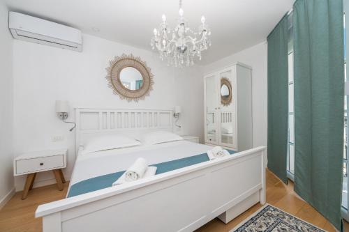 a white bedroom with a large bed and a chandelier at ORKA 5 in Promajna