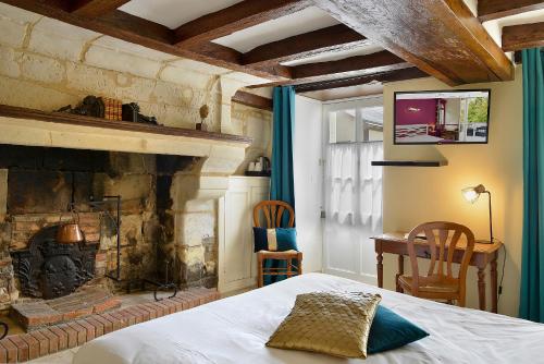 1 dormitorio con 1 cama y chimenea en Logis Manoir De La Giraudière, en Beaumont-en-Véron