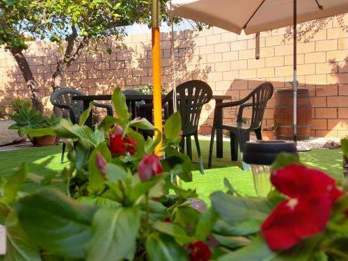 a patio with chairs and a table with red flowers at Su Fassoi Cabras in Càbras