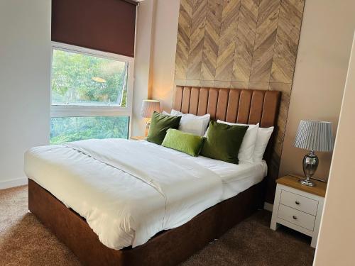 um quarto com uma cama grande e almofadas verdes em Ebony Apartments MK em Milton Keynes