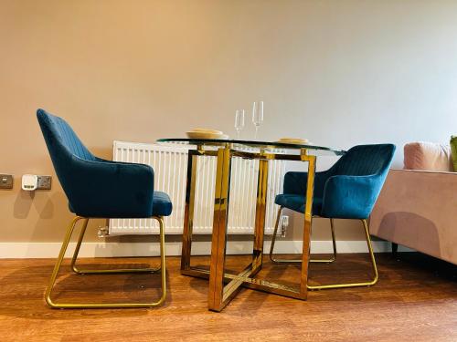 uma mesa de jantar com duas cadeiras azuis e uma mesa em Ebony Apartments MK em Milton Keynes