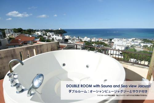 a bath tub on a balcony with a view of the ocean at FIRST STREET Okinawa Yomitan-son Oceans -SEVEN Hotels and Resorts- in Yomitan