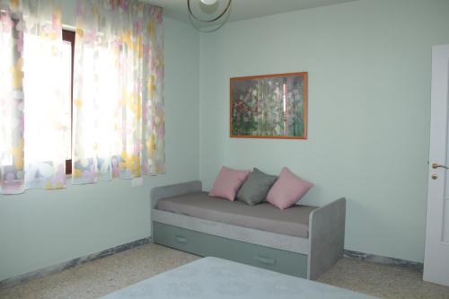 Habitación con cama con almohadas rosas y ventana. en Il garusolo, en Pineto