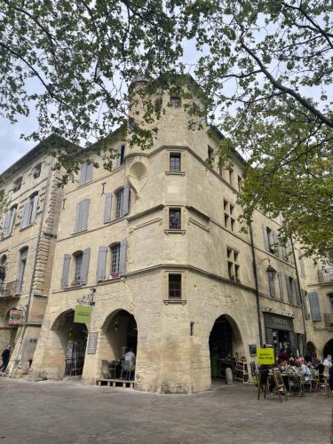 um grande edifício de pedra com pessoas sentadas fora dele em Le Cherche Midi - Appartement centre historique d'Uzès em Uzès