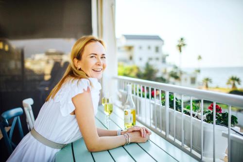 a woman sitting on a balcony with a glass of wine at Domus Bat Galim Hotel in Haifa
