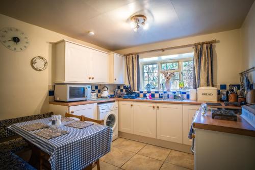 a kitchen with a table and a sink and a stove at Lower Mill 2 Cottage Broadway in Broadway