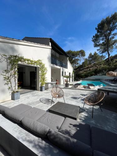 patio con sofá, sillas y piscina en Arty Provence, piscine chauffée en Saint-Étienne-du-Grès