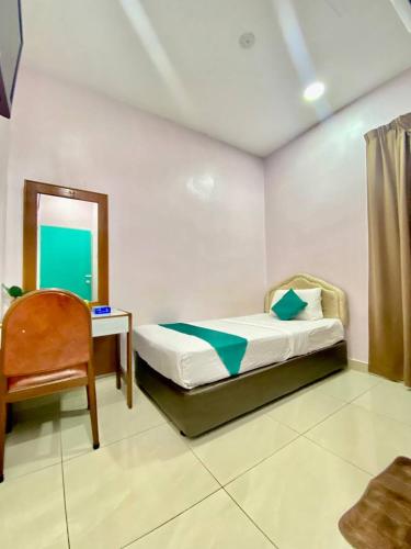 a bedroom with a bed and a chair and a mirror at Sun Tree Hotel in Kampong Kerayong