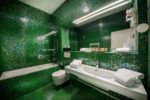 La salle de bains verte est pourvue d'une baignoire, de toilettes et d'un lavabo. dans l'établissement Rimske Terme Resort - Hotel Sofijin dvor, à Rimske Toplice