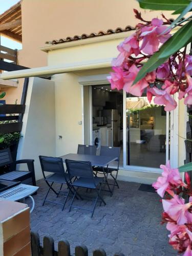 une table et des chaises sur une terrasse ornée de fleurs roses dans l'établissement Plage de la Roquille, au Cap d'Agde
