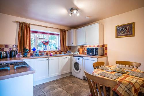 a kitchen with a washing machine and a table with chairs at Lower Mill 1 Cottage Broadway in Broadway