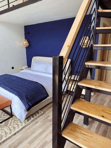 a bedroom with a bed with a blue wall and stairs at Khoj Resorts Shigar in Shigar
