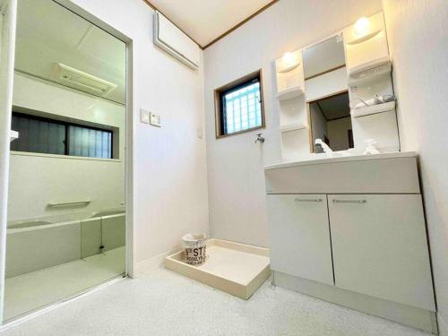 Baño blanco con lavabo y espejo en 【NEW】鶴橋駅徒歩２分/トイレ•浴室複数あり/３階建一軒家車庫付き, en Osaka