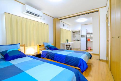 1 dormitorio con 2 camas y sábanas azules en 【NEW】鶴橋駅徒歩２分/トイレ•浴室複数あり/３階建一軒家車庫付き, en Osaka