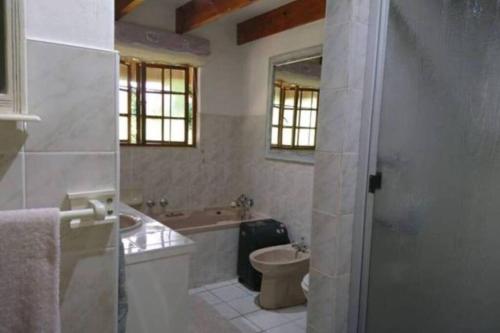 a bathroom with a tub and a toilet and a sink at The Underberg Cottage in Underberg