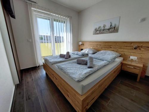 Un dormitorio con una gran cama de madera con almohadas. en Gold Apartmani Kozarac, en Kozarac
