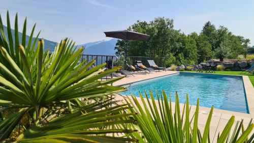 une piscine avec des chaises et un parasol dans l'établissement Le Refuge du Montagnard, à Marthod