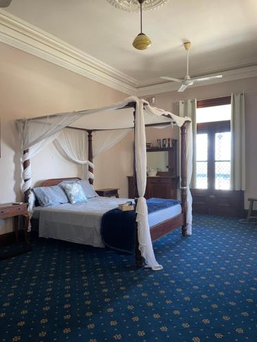 ein Schlafzimmer mit einem Himmelbett und einem blauen Teppich in der Unterkunft 122 on Charlotte in Cooktown
