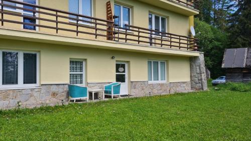 a house with two chairs and a table in the yard at Tatry Ela Big apartment in Vysoké Tatry