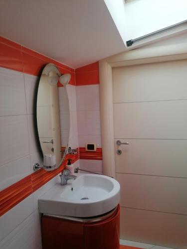 uma casa de banho com um lavatório, um espelho e uma porta em Romantica mansardina in centro città em Pescara