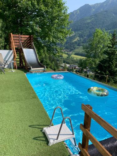a swimming pool with a slide and a chair in the grass at Appartementhaus Gastein / Haus Sammie in Bad Gastein