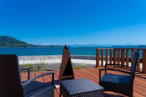 a deck with chairs and a table and a view of the water at GLAMPDOME SETOUCHI-SHIMANAMI in Onomichi