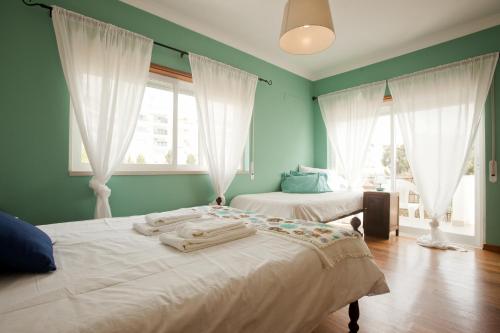 2 Betten in einem Zimmer mit grünen Wänden und Fenstern in der Unterkunft Ericeira Chill Hill Hostel & Private Rooms in Ericeira