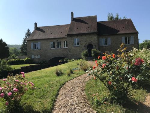 une vieille maison en pierre avec des fleurs dans la cour dans l'établissement Le Moulin de Villiers, à Gudmont-Villiers