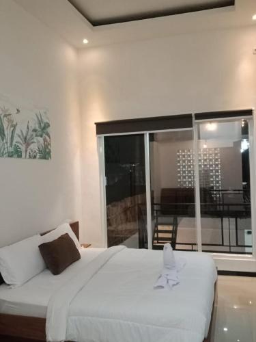 een slaapkamer met een groot wit bed en een balkon bij Cahaya 1 Guest House in Songgoriti