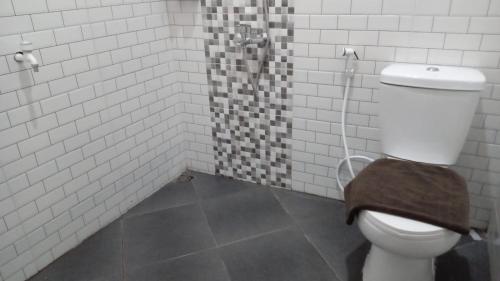 een badkamer met een toilet en een douche met witte tegels bij Cahaya 1 Guest House in Songgoriti