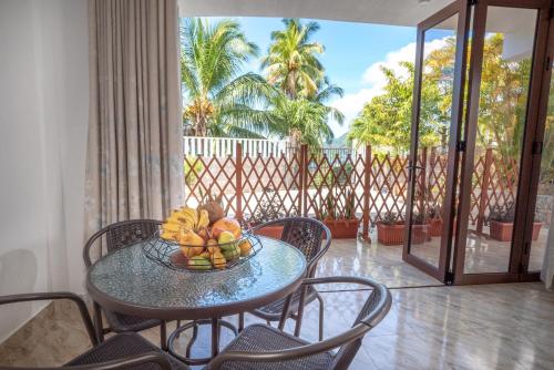 a table with a bowl of fruit on a balcony at La Belle Residence Self Catering Accommodation in Beau Vallon