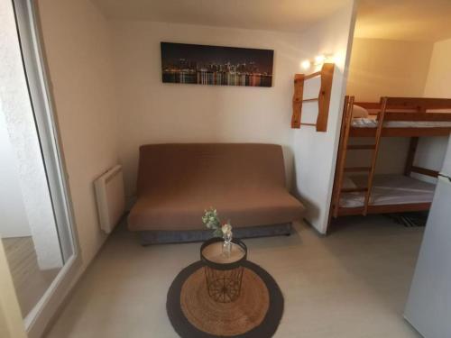 um pequeno quarto com um sofá e uma mesa em Studio Cap Coudalère vue lac marin et climatisé tout confort proche des plages em Le Barcarès