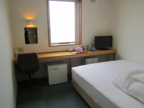 Schlafzimmer mit einem Bett und einem Schreibtisch mit einem Computer in der Unterkunft Hotel Nishi In Fujisan in Fuji