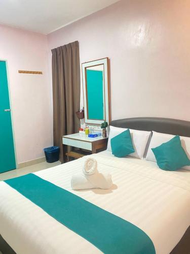 a bedroom with a large bed with blue and white pillows at Sun Tree Hotel in Kampong Kerayong