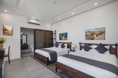 a hotel room with two beds and a television at Charm Champion Villa Hoian in Hoi An