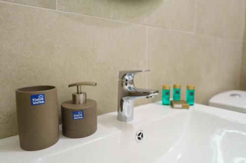 a bathroom sink with a faucet and two trash cans at Castelana Infinity Beach Pool&Spa Mamaia Nord in Mamaia Sat/Năvodari