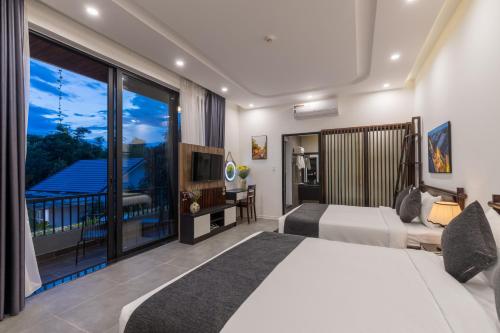 a hotel room with two beds and a balcony at Charm Champion Villa Hoian in Hoi An