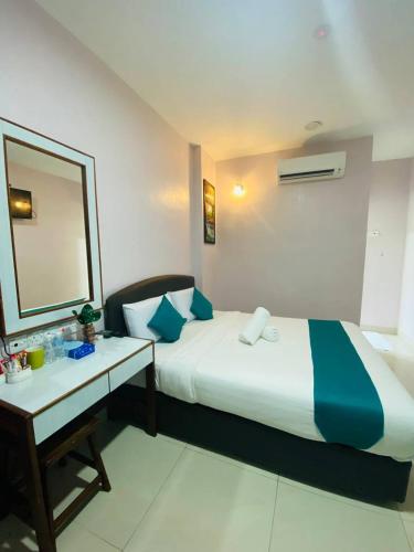 a bedroom with a bed and a desk and a mirror at Sun Tree Hotel in Kampong Kerayong