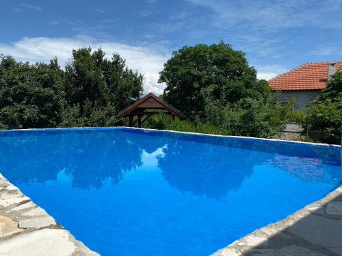 a blue swimming pool with a gazebo at Green House Pejovic in Podgorica