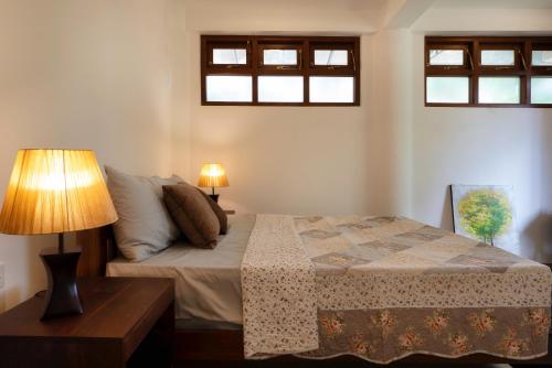 a bedroom with a bed with a lamp and two windows at Kandy Tree Tops in Kandy