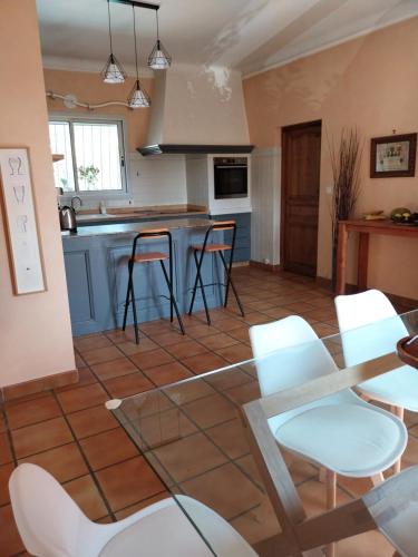 a kitchen with white chairs and a table at Jolie maison provençale. in Saint-Estève-Janson