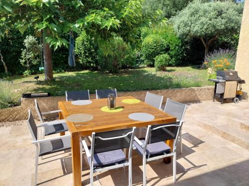 uma mesa de madeira e cadeiras num quintal em Jolie maison provençale. em Saint-Estève-Janson