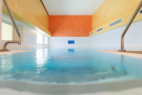 a swimming pool with blue water in a building at Alphotel Ettal in Ettal