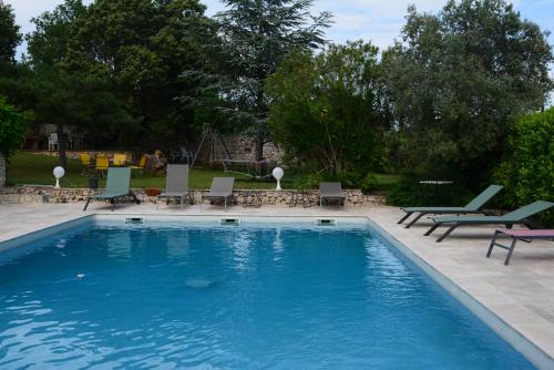 a large swimming pool with chairs and a table at Le Mas De Cocagne in Saint-Maximin-la-Sainte-Baume