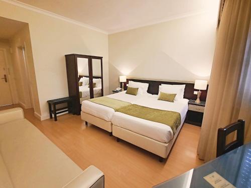 a hotel room with a large bed and a table at Hotel Aleluia in Fátima