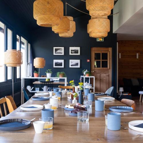 Una gran mesa de madera con platos y lámparas azules. en Maison Cimes, en Les Orres