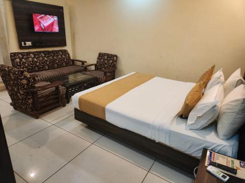 a bedroom with a bed and a couch and a tv at Hotel City Lite Near IGI Airport Delhi in New Delhi