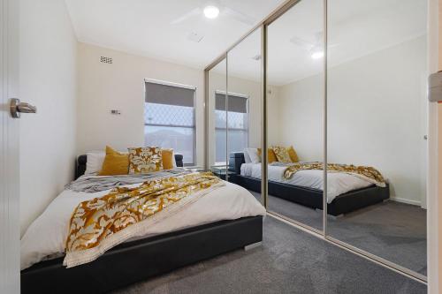 a bedroom with two beds and a mirror at West Beach House 4U in Henley Beach South