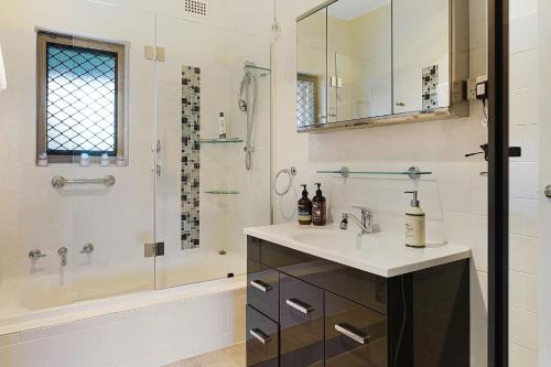 a bathroom with a sink and a shower and a tub at West Beach House 4U in Henley Beach South
